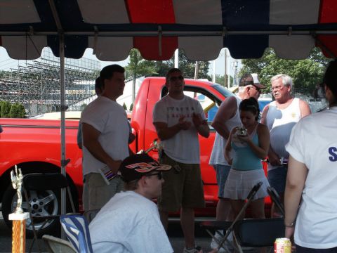 2001 Mercury Grand Marquis - A red pickup truck is visible at a car show with several people standing around.