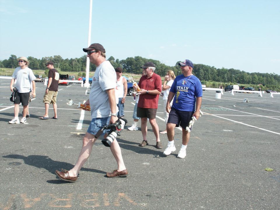 People walking in a parking lot with trees and a blue sky