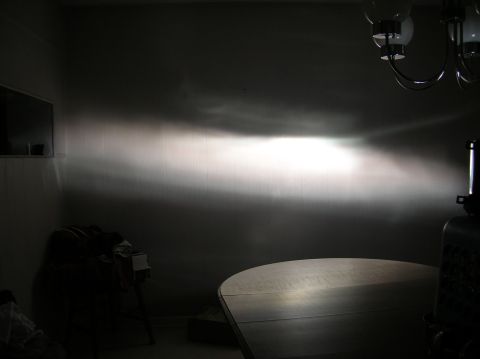 1996 Toyota 4Runner - A bright headlight beam pattern is cast onto a wall, illuminating the room and a table below.