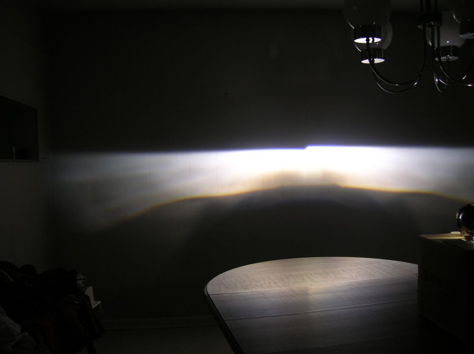 Headlight beam pattern projected onto a wall, with a table in the foreground