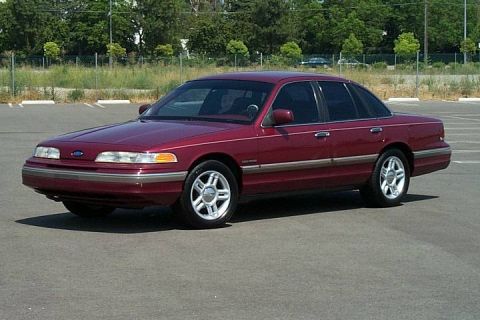 1992 Ford Crown Victoria - A maroon Ford Crown Victoria is shown from the front three-quarter view in an outdoor parking lot.