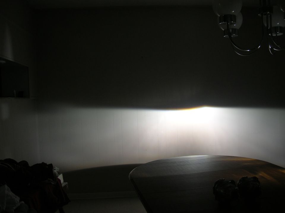 Headlight beam pattern projected onto a wall, with a table in the foreground