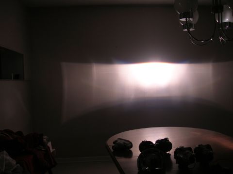 1996 Toyota 4Runner - A bright headlight beam pattern is cast onto a wall, with a table holding several bulbs in the foreground.
