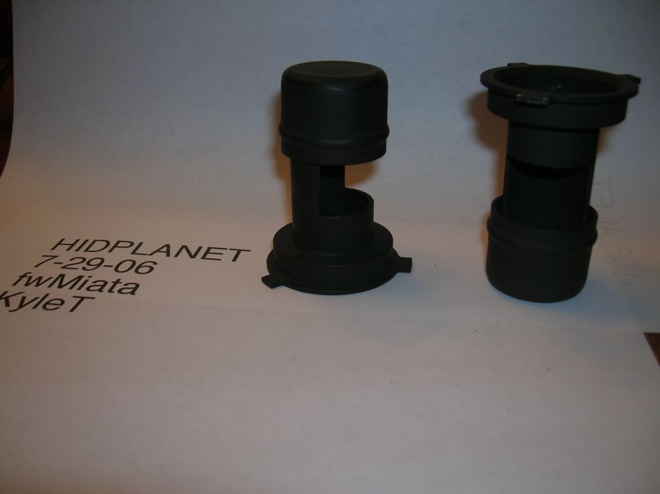 Two black plastic headlight dust caps on white paper with text