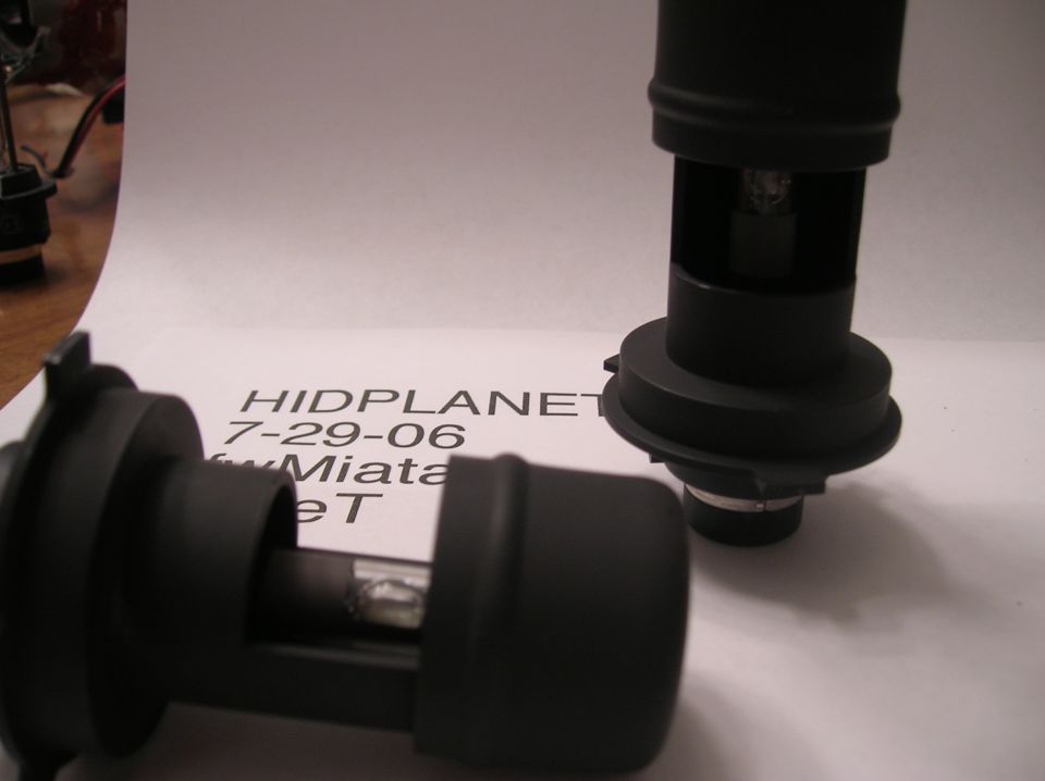 Two HID headlight bulbs on a paper with text HIDPLANET 7-29-06 Miata eT