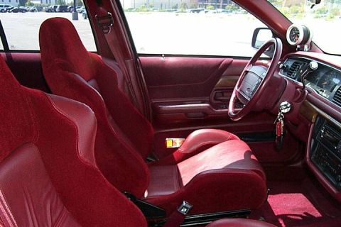 1992 Ford Crown Victoria - Interior of a car with an all-red leather cabin, showing aftermarket red racing-style bucket seats, a red dashboard and door panel, a leath…