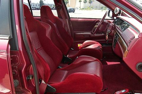 1992 Ford Crown Victoria - Interior of a sedan showing custom red upholstery with aftermarket bucket-style front and rear seats, viewed from the driver's side door op…
