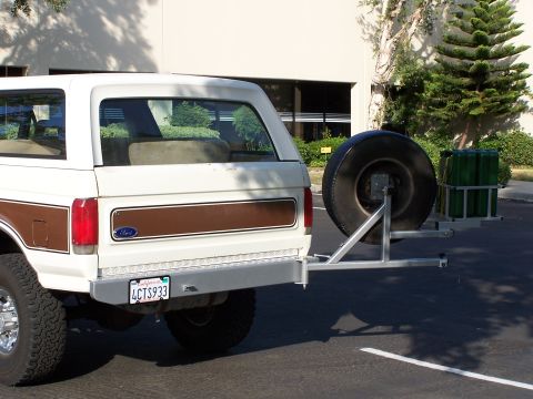 1988 Ford C-350 (Centurion Conversions) - This Ford Bronco, likely from the 1980s, has a rear-mounted spare tire and a cargo rack with green containers.