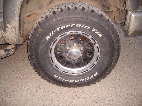 2000 Chevrolet Tahoe - Close-up of a BFGoodrich All-Terrain T/A tire mounted on a multi-spoke black rim with a chrome accent ring.