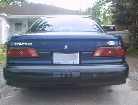 1993 Ford Taurus - The rear of a blue Ford Taurus is shown, with a license plate and taillights visible.