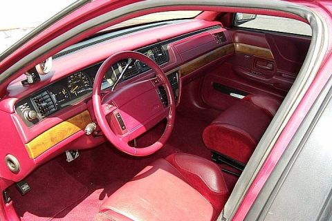 1992 Ford Crown Victoria - Interior view of a sedan with red/burgundy upholstery, showing the driver's side dashboard, steering wheel with a Ford emblem, faux wood tr…
