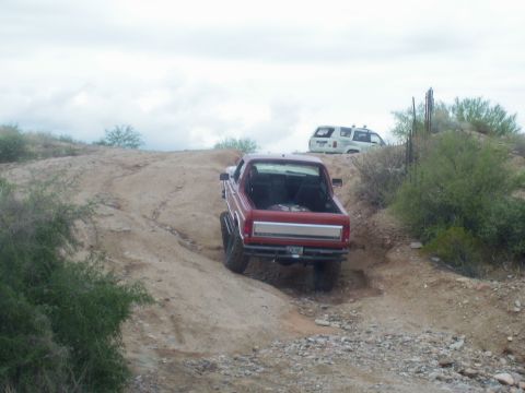 1991 Ford Bronco - Two off-road vehicles navigate a dusty, hilly terrain under an overcast sky.