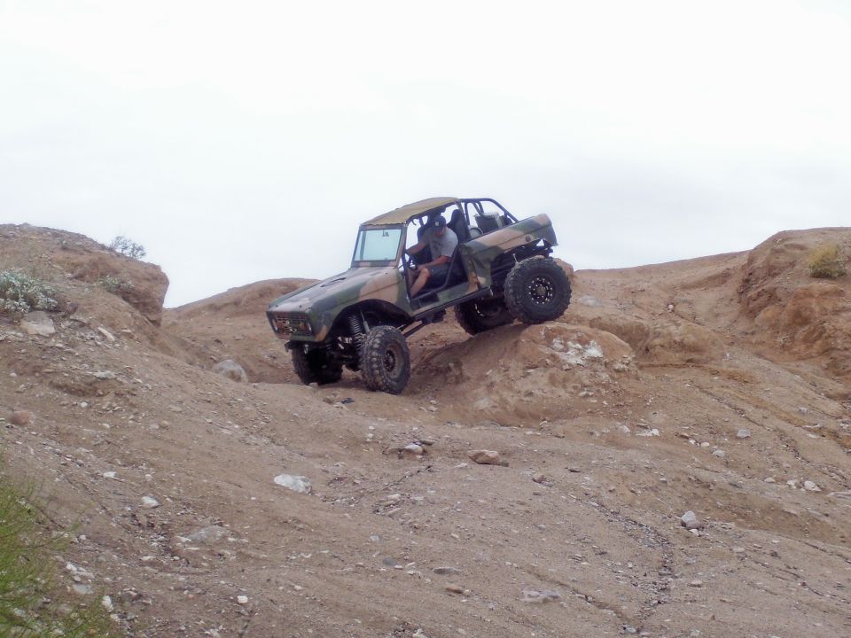 Custom off-road vehicle with camouflage paint climbing a rocky hill