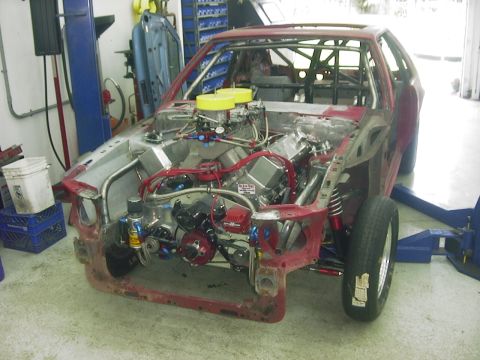 1990 Ford Mustang - A heavily modified vehicle's engine bay is shown, a large engine and custom racing components.
