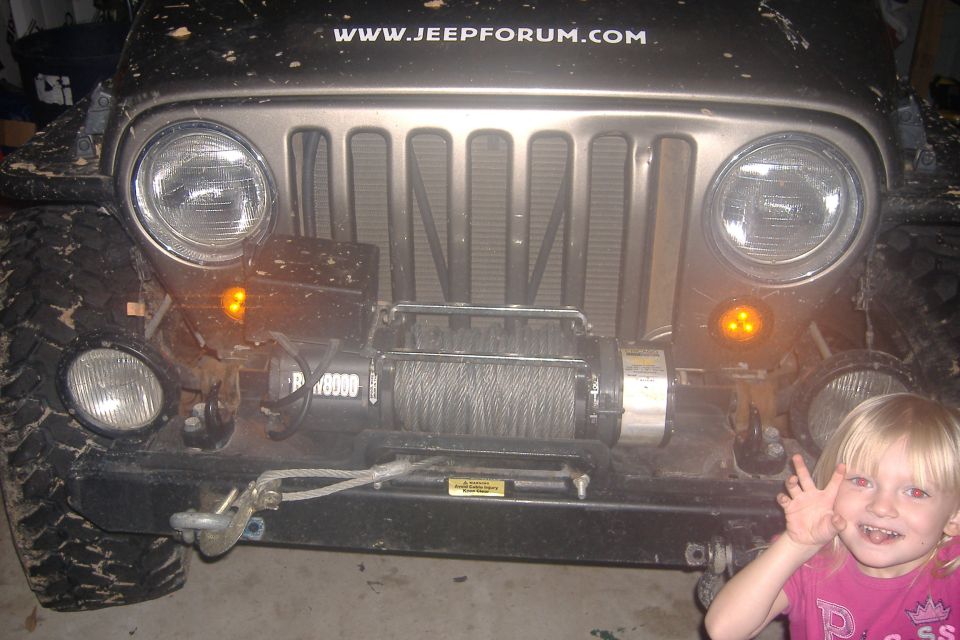 2004 Jeep Wrangler front end with winch mounted on bumper. Website www.jeepforum.com visible on hood