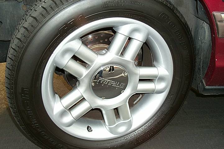 Silver five-spoke Fittipaldi alloy wheel with BFGoodrich tire on red car