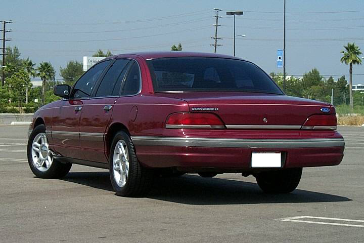 Maroon Ford Crown Victoria LX sedan seen from rear 3/4 angle in a parking lot
