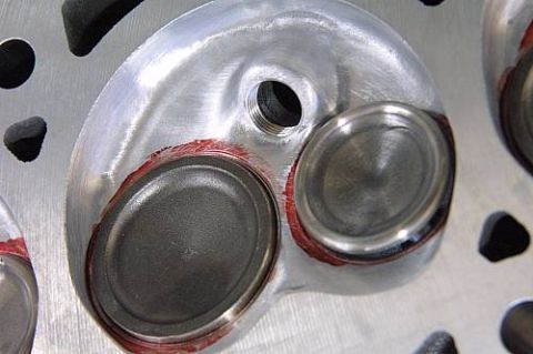 1992 Ford Crown Victoria - Close-up of a freshly machined aluminum cylinder head combustion chamber showing two valve seats (intake and exhaust), a threaded spark plu…