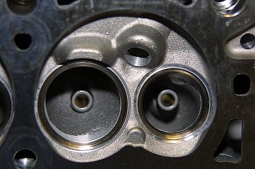 Close-up of cylinder head combustion chamber with two machined valve seats and spark plug hole