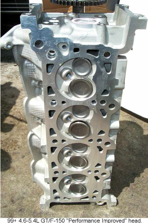 1992 Ford Crown Victoria - Bare aluminum cylinder head stood on end on a concrete driveway, showing the combustion-chamber deck face with four two-valve chambers and…