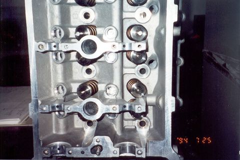 1992 Ford Crown Victoria - Close-up of a bare aluminum cylinder head resting on its side, showing seated valve springs and the machined camshaft bearing saddles and r…