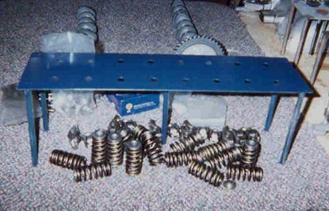 1992 Ford Crown Victoria - A pile of dual valve springs with retainers and locks laid out on carpet in front of a blue-painted parts organizing stand, with two camsha…