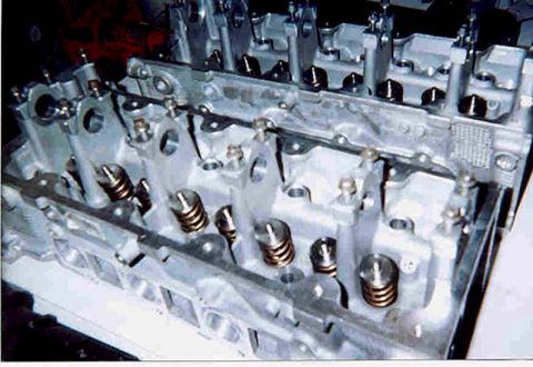 1992 Ford Crown Victoria - A close-up of an aluminum cylinder head on a workbench, showing installed valves with coil valve springs and retainers seated in the combus…