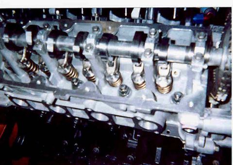 1992 Ford Crown Victoria - Close-up of an aluminum overhead-cam cylinder head with the valve cover removed, showing the camshaft in its bearing caps, roller followers…