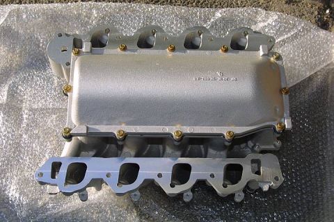 1992 Ford Crown Victoria - A cast-aluminum V8 intake manifold sits on bubble wrap, showing its upper plenum with a raised casting number and brass fittings above a lo…