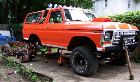 1978 Ford Bronco - This orange Ford Bronco is in the process of being worked on, with its front end lifted and parts removed.