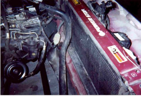 1992 Ford Crown Victoria - Close-up down the passenger side of an open engine bay, showing a red-tanked aluminum radiator with 'Power Stroke' lettering and a K&N stic…
