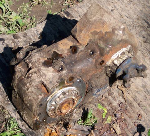 1978 Ford Bronco - This rusty transfer case is resting on weathered wooden planks outdoors.