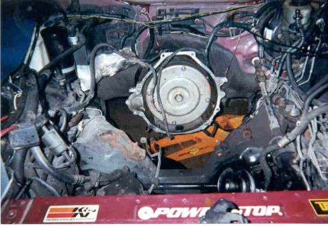 1992 Ford Crown Victoria - Engine bay of a maroon car with the engine removed, exposing the automatic transmission's torque converter and bellhousing at the firewall,…