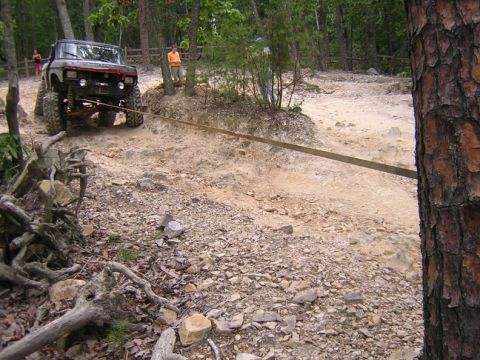 1979 Ford Bronco - An off-road vehicle with oversized tires is being towed up a rocky incline by a tow strap.