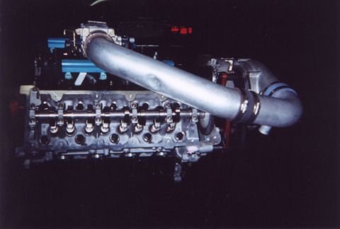 1992 Ford Crown Victoria - Flash photo in a dark shop of a bare overhead-cam cylinder head with the valve cover removed, showing the camshaft, bearing caps and rocker…