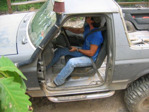 1992 Ford Mustang - A man is seen driving a heavily modified off-road vehicle, equipped with a snorkel for deep water crossings.