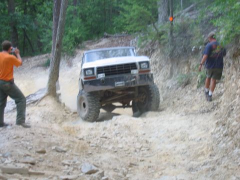 1992 Ford Mustang - A modified off-road vehicle navigates a challenging dirt path with spectators present onlookers.