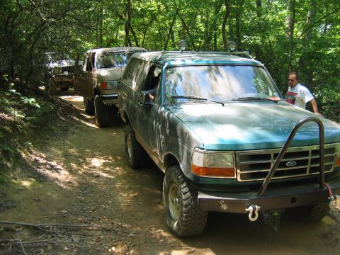 1992 Ford Mustang - Two Ford Broncos navigate a wooded trail during an off-road excursion.