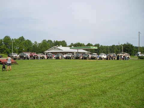 1996 Ford Bronco - A group of SUVs and trucks are parked in a grassy area outside a gas station.