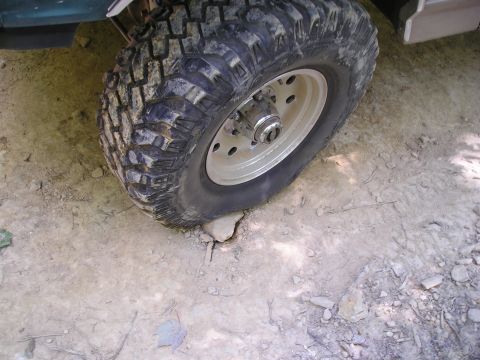 1996 Ford Bronco - A close-up view of a vehicle's tire and wheel navigating rough terrain.