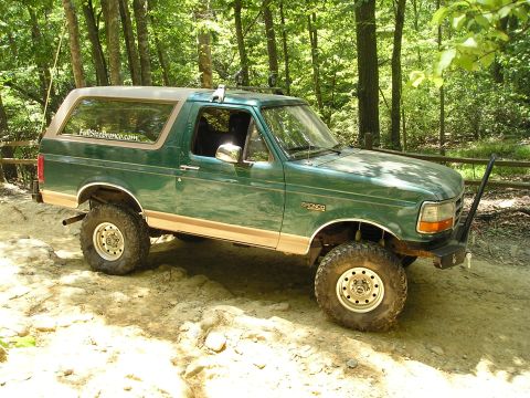 1996 Ford Bronco - This 1996 Ford Bronco is shown off-roading on a dirt trail surrounded by trees.