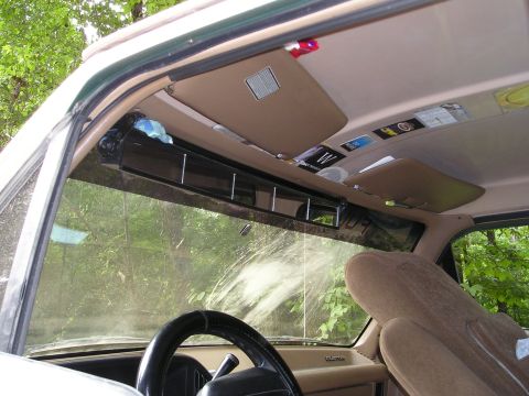 1996 Ford Bronco - The interior of a vehicle is shown, focusing on the dashboard, steering wheel, and overhead storage bins filled with various items.
