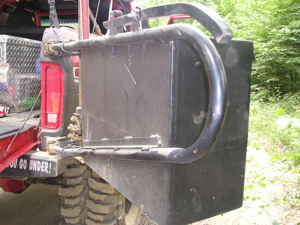 Rear view of a red SUV with a large external fuel tank, roll cage, and "YOU GO UNDER!" sticker on bumper