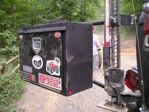 1996 Ford Bronco - A toolbox and Hi-Lift jack are mounted on the side of a vehicle, with another vehicle and person visible in the background.