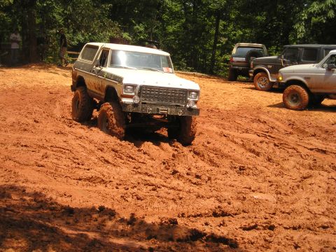1996 Ford Bronco - A white Ford Bronco navigates a muddy off-road course with other vehicles nearby.