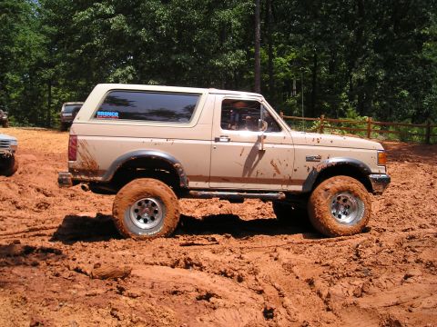 1996 Ford Bronco - Muddy 1996 Ford Bronco navigating off-road terrain with another vehicle partially visible.