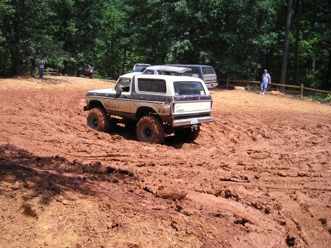 1996 Ford Bronco - A classic Ford Bronco navigates a muddy off-road course with other vehicles present.