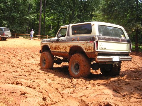 1996 Ford Bronco - A lifted 1978 Ford Bronco navigates a muddy off-road course, with another vehicle visible in the background.