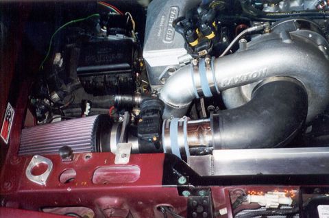 1992 Ford Crown Victoria - Supercharged engine bay of a red Ford, showing a polished Paxton centrifugal supercharger mounted on the passenger side with cast tubing an…