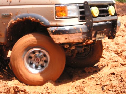 1996 Ford Bronco - Off-roading in a 1996 Ford Bronco, front tire deep in mud.